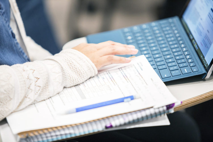 Close up of a student with their notebook and laptop