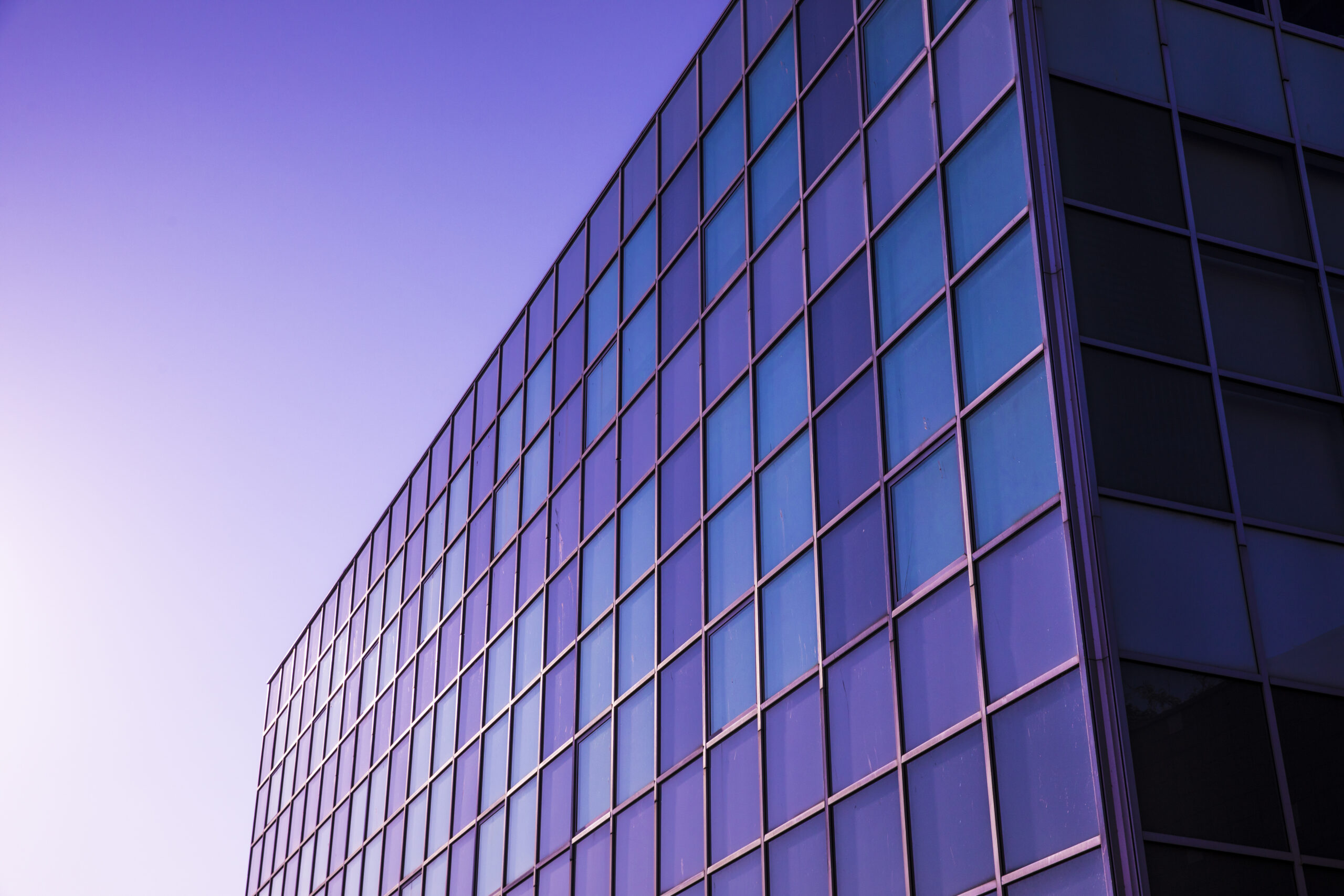 Side of building with many windows with a purple hue